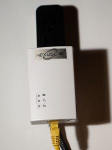 A NexusLink plugged into a power strip, with a ghastly yellow Ethernet plugged into it.
