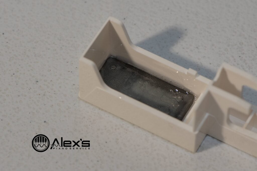 Closeup of lead-weight installed with J-B Weld epoxy under a keyboard key.